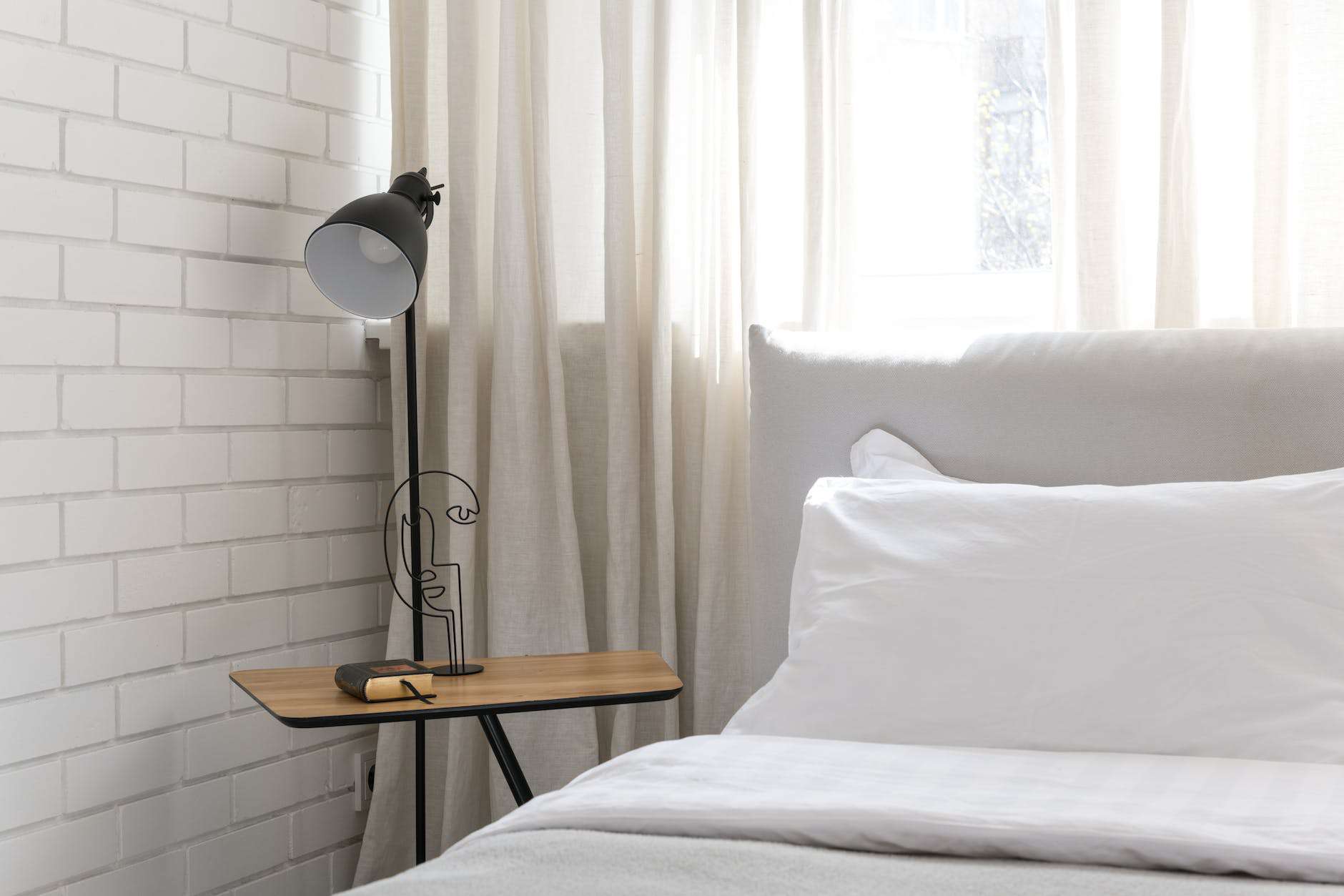 black and white table lamp on brown wooden table beside bed