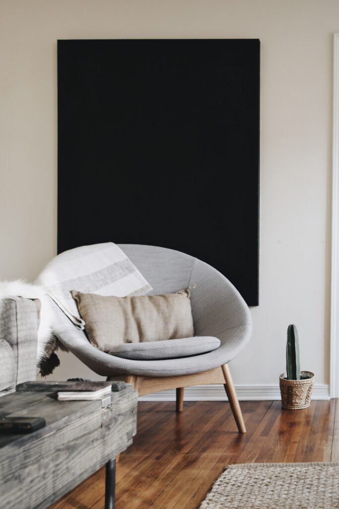 High-impact oversized art acts as a focal point, even in it's most basic form. Here, a plain black canvas hands behind an oval gray chair, adding strong contrast and visual interest to an otherwise plain room. 