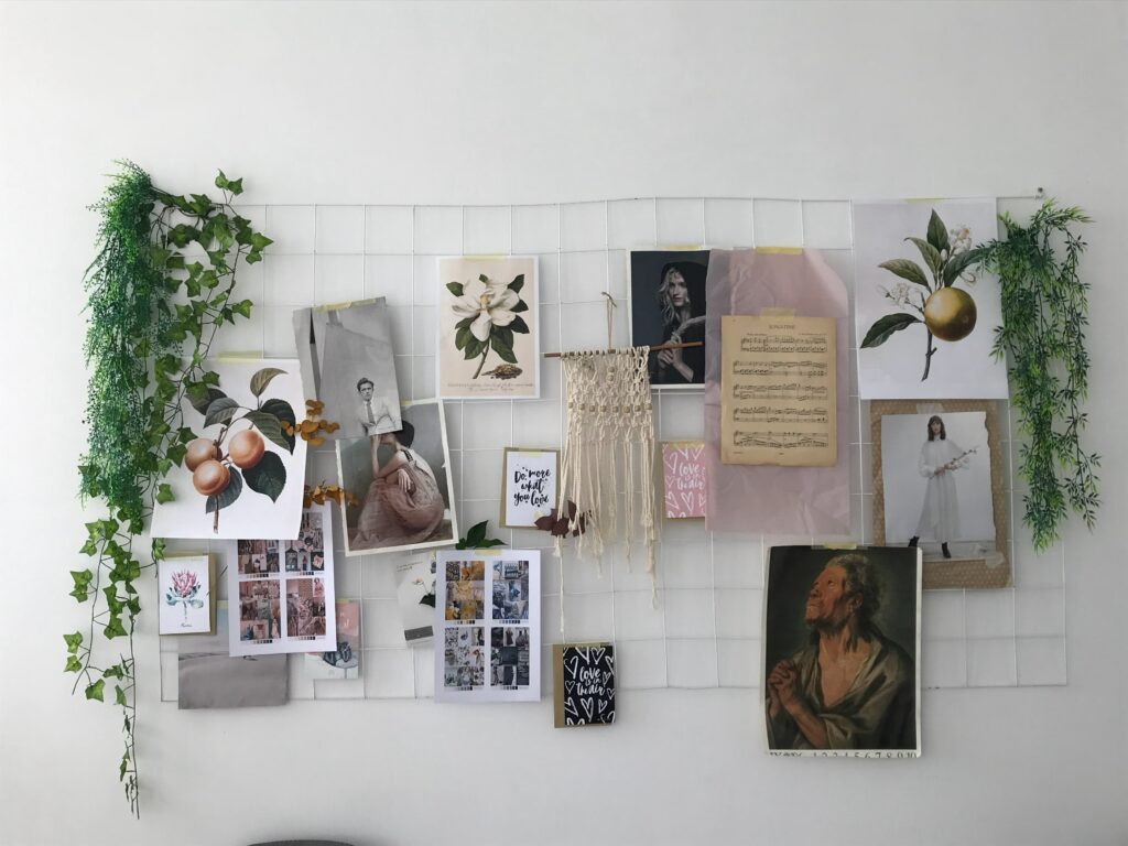 A mood board taped to a wall, featuring vintage art, fruit, flowers, and personal photographs. 