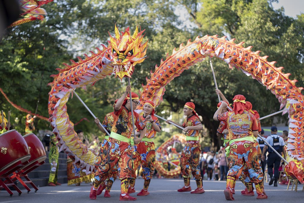 Scene of an Asian new year festival featuring a red dancing dragon choreographed by six men dressed in colorful fabrics
