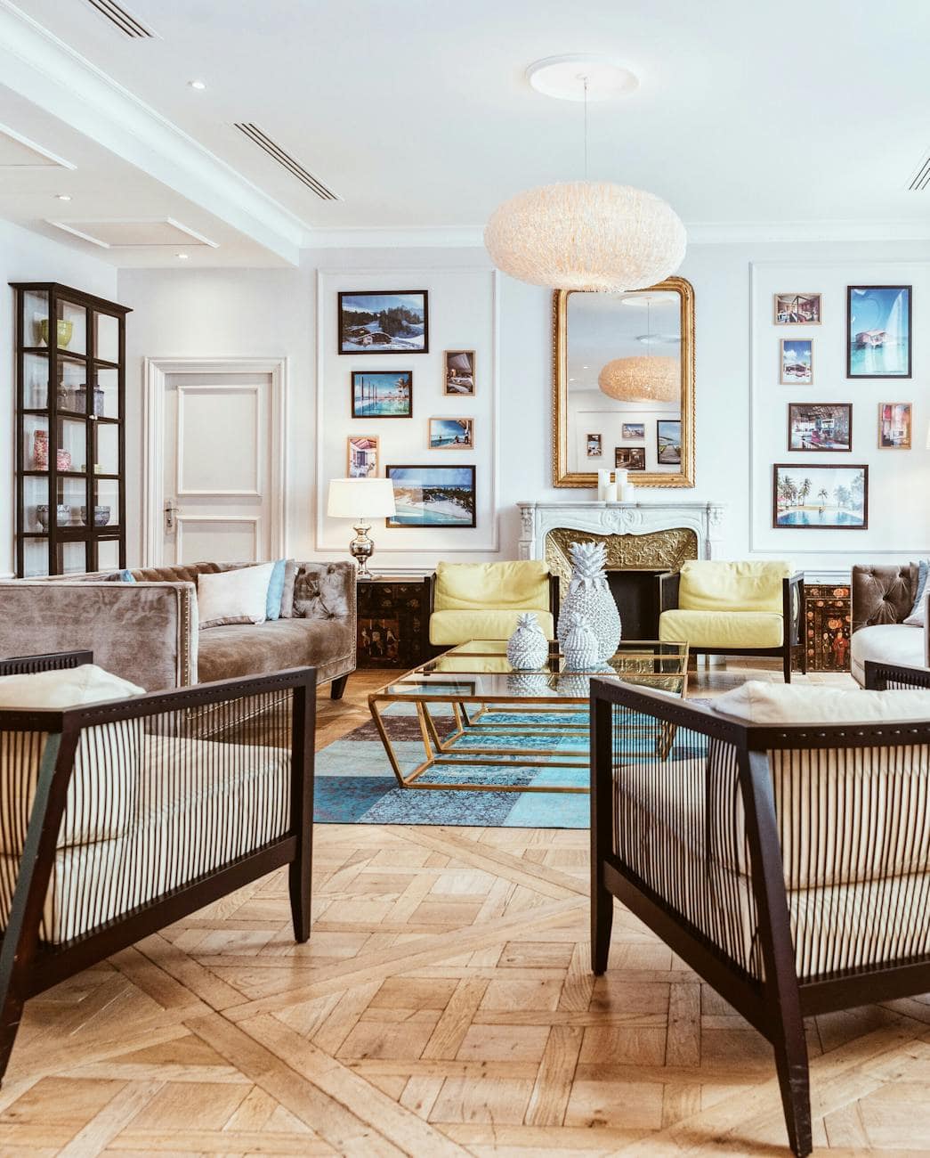 a layered living room featuring sculptural lighting, modern photography, aged brass and bronze, and vintage parquet flooring. 